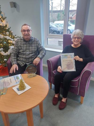 A picture of Mr and Mrs Palmer with their Best Floral Display winners trophy and certificate